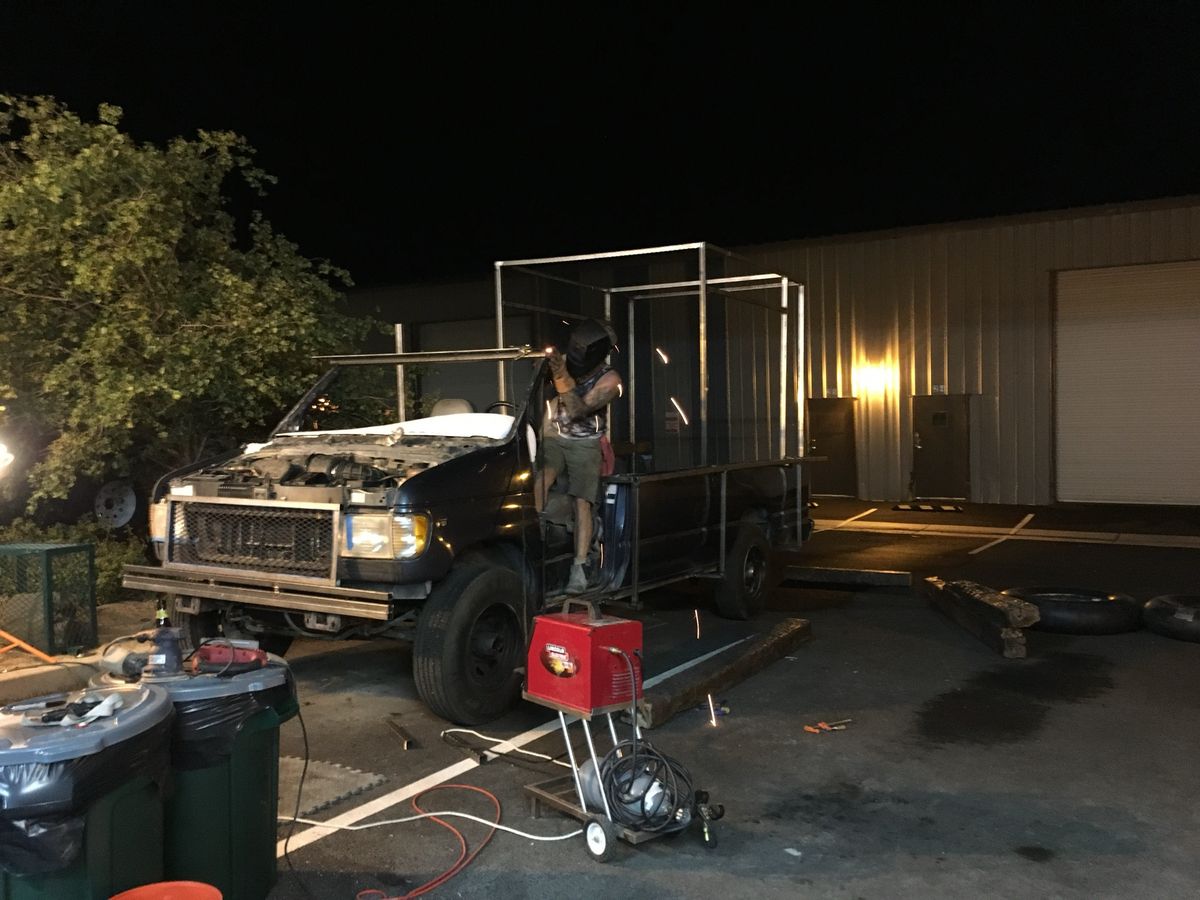 Welding the new steel cage onto the stripped van at night