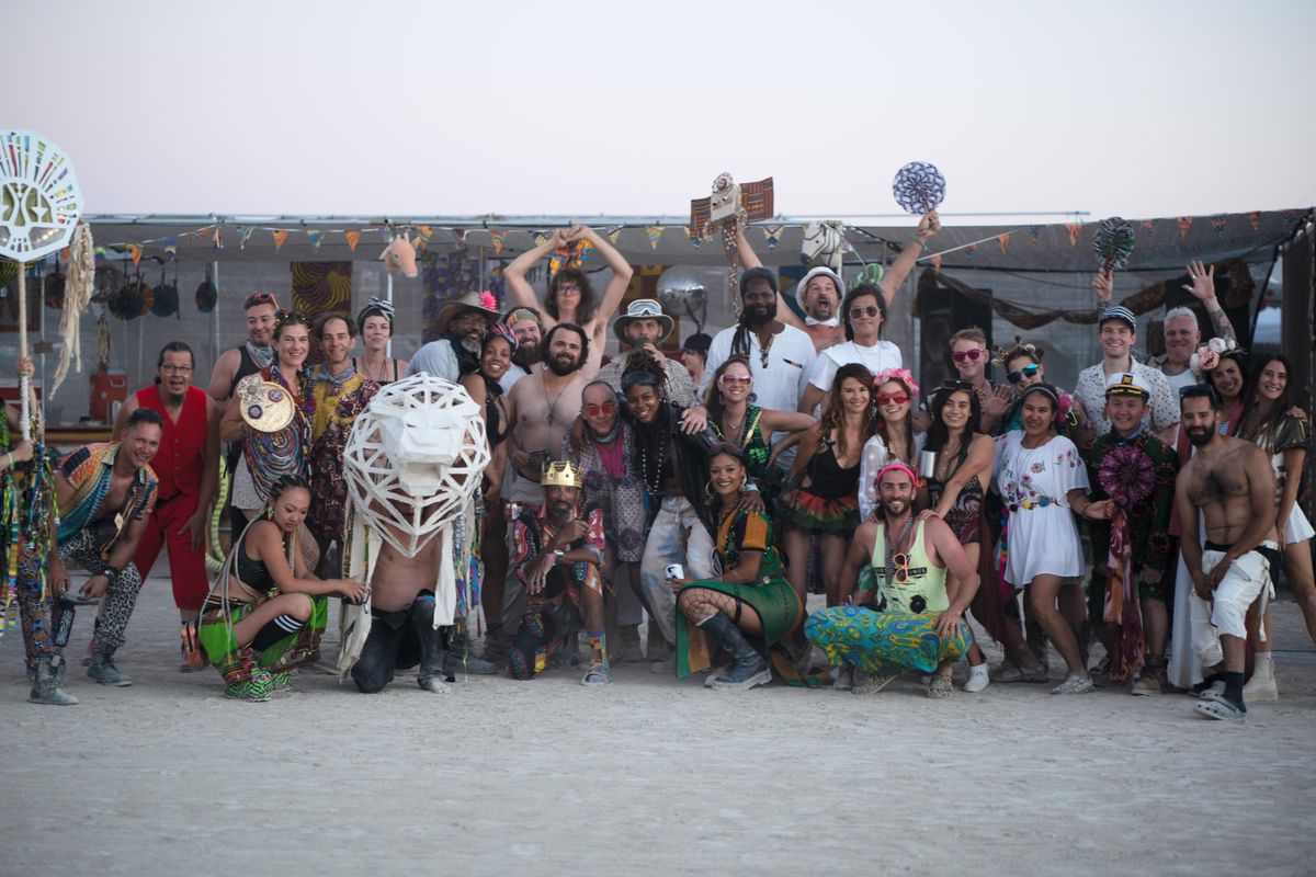 The 2022 Sundowners crew posing in front of camp, a white lion costume at the front