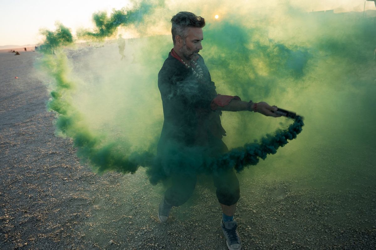 A campmate swirling a trail of green smoke across the playa