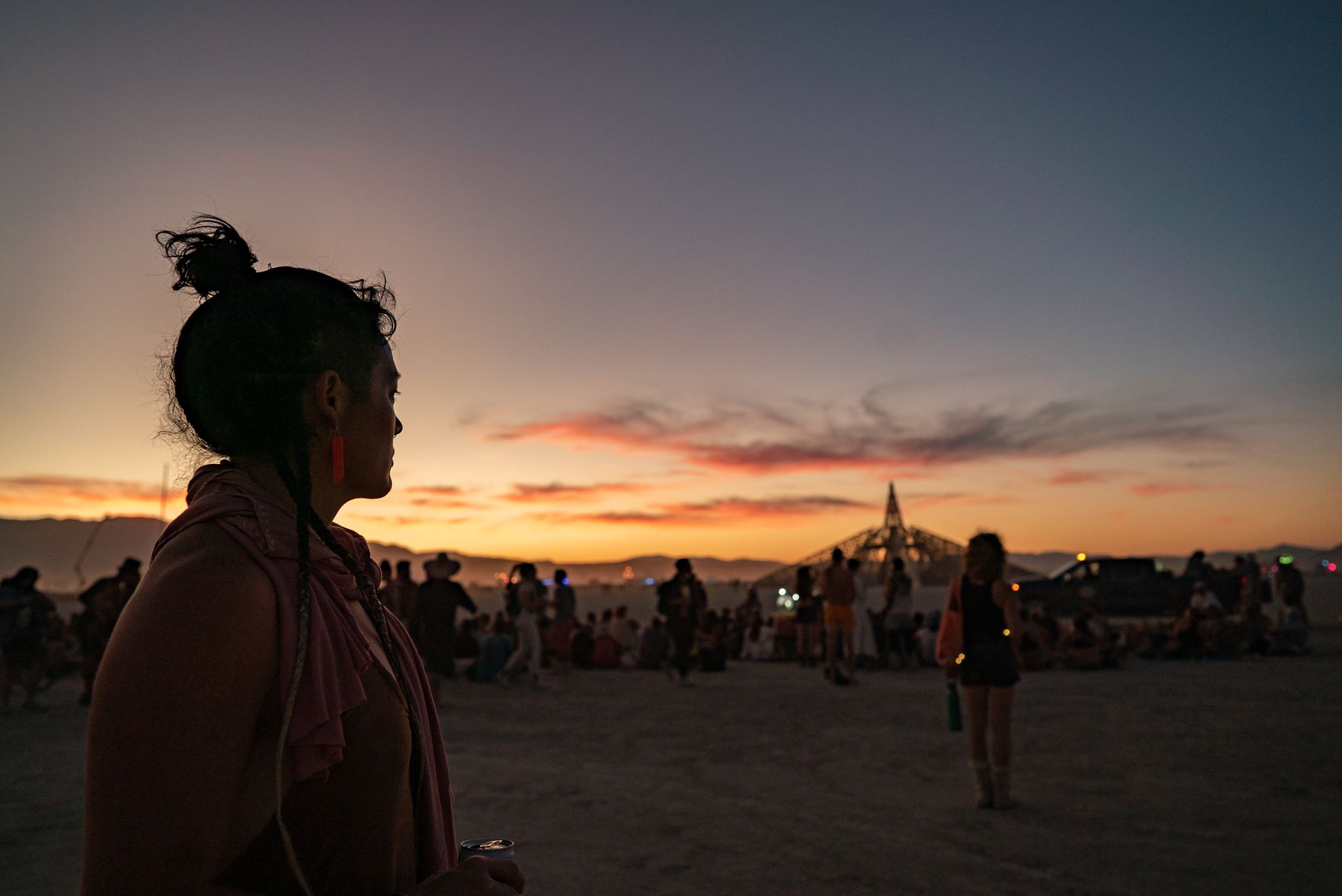 A campmate watching the sunset over a crowd gathered on the playa