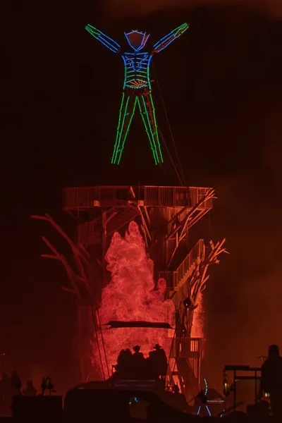 the man lit up above a wall of fire