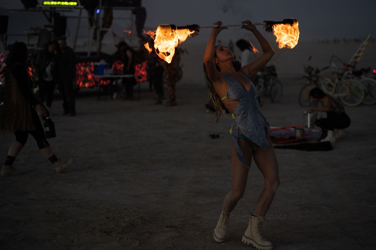 A fire spinner performing on the playa near Rexan at dusk
